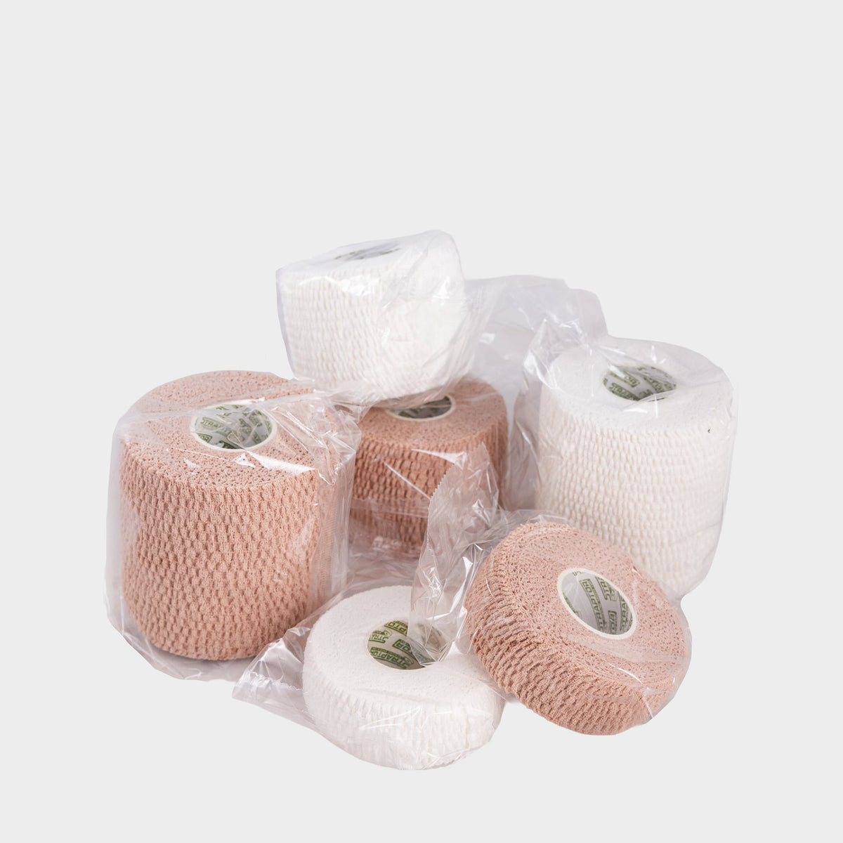 Straptor cohesive bandage rolls in tan and white, grouped on a plain background