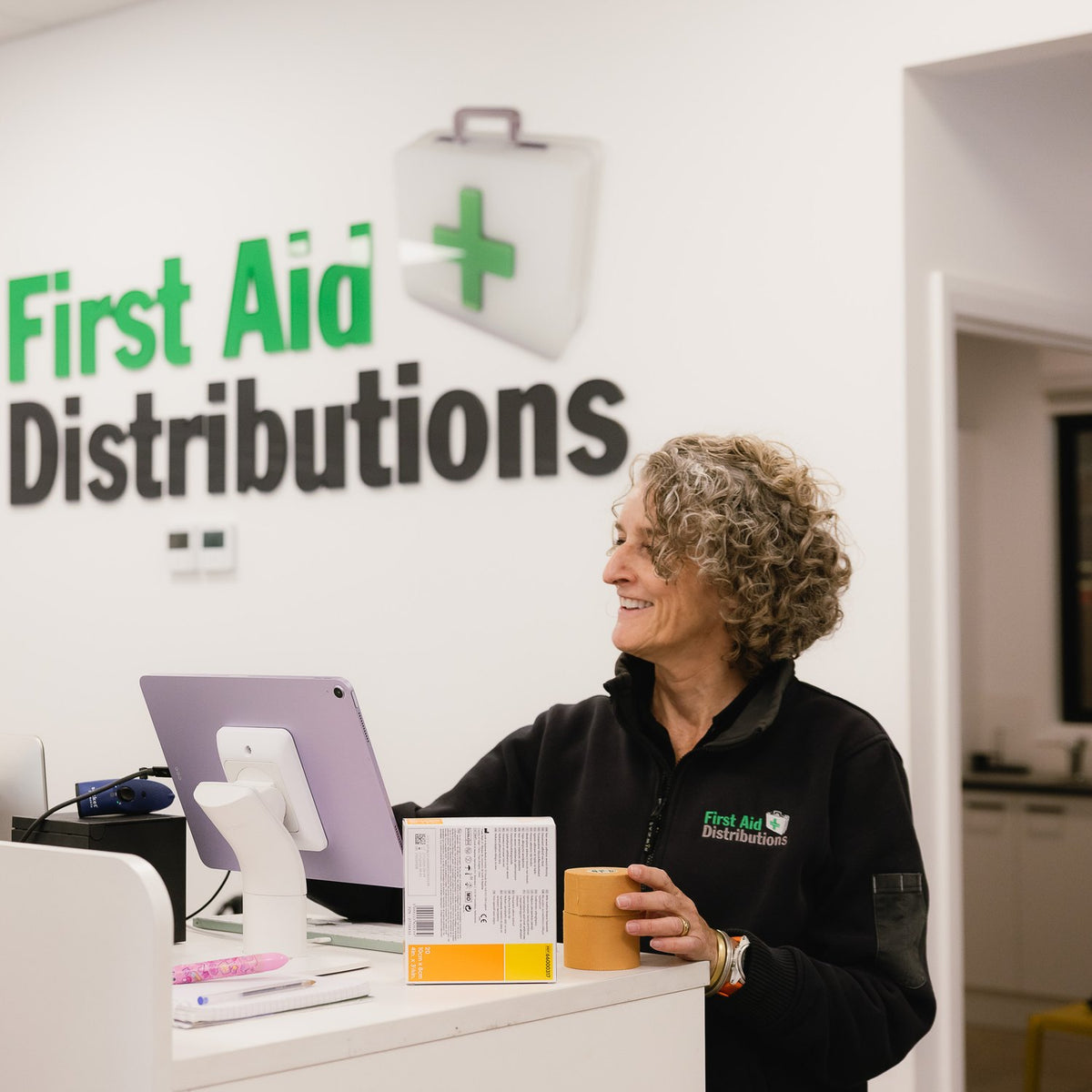 A team member serving a customer at the East Bendigo counter, holding a roll of rigid tape